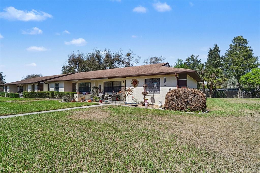 A single-story residential building with a brown roof, beige stucco exterior, and front lawn — 12435 ORANGEWOOD CIRCLE, TAVARES, FL