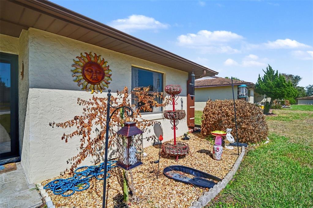 The exterior of a house features a sun wall decoration, landscaping, and decorative garden items — 12435 ORANGEWOOD CIRCLE, TAVARES, FL
