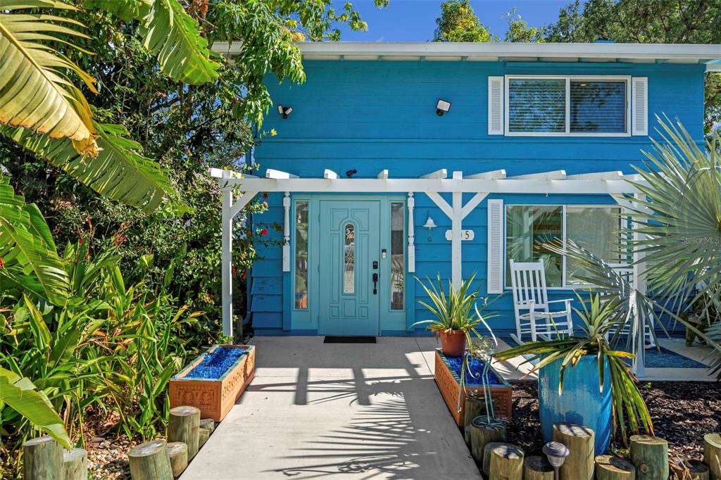 A bright blue two-story house features a white pergola over the front entrance and walkway — 105 TUCKER AVENUE, SARASOTA, FL