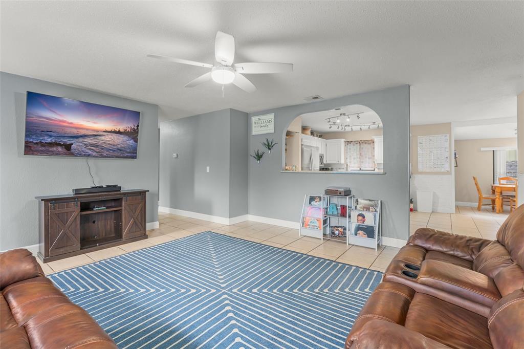 A living room features a blue patterned rug, brown leather sofas, and a wall-mounted television — 1703 VICTORY PALM DRIVE, EDGEWATER, FL