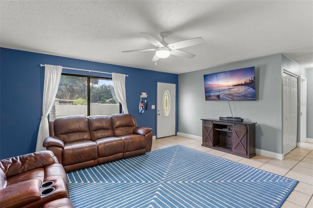A living room features a blue accent wall, brown leather sofas, and a large area rug — 1703 VICTORY PALM DRIVE, EDGEWATER, FL