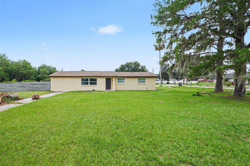 A single-story, tan-colored house sits on a large, grassy lot with mature trees — 9220 MCINTOSH ROAD, DOVER, FL
