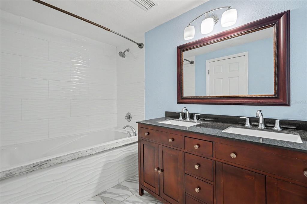 A bathroom features a double vanity with a dark wood cabinet and a tiled tub — 9220 MCINTOSH ROAD, DOVER, FL