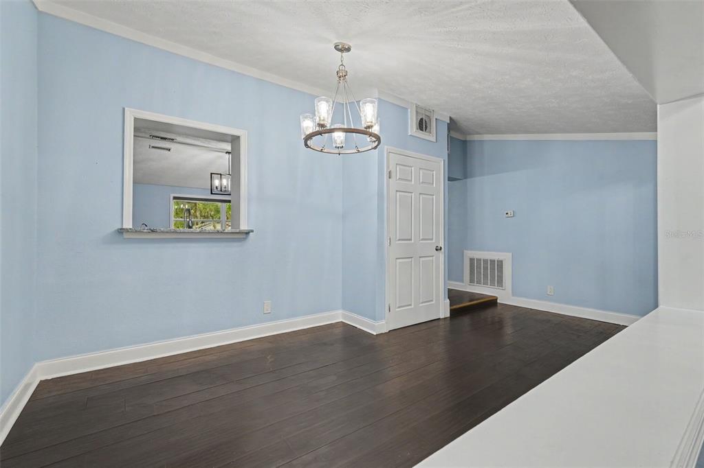 A dining room with light blue walls, dark wood flooring, and a modern chandelier — 9220 MCINTOSH ROAD, DOVER, FL