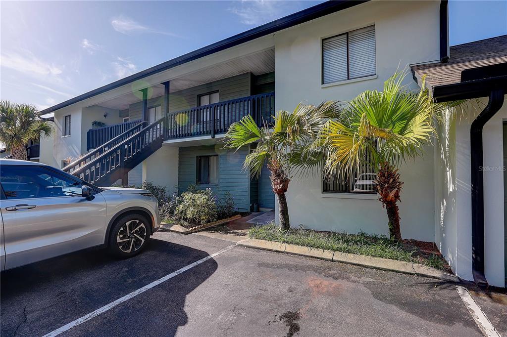 A two-story apartment building exterior with a staircase, balcony, and palm trees in the parking lot — 3708 GREENERY COURT UNIT 108, TAMPA, FL