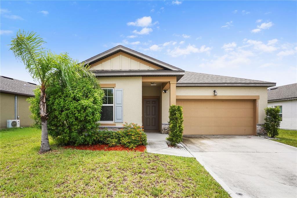 A single-story suburban house with a tan stucco exterior, a two-car garage, and a palm tree — 3004 NEVERLAND DRIVE, NEW SMYRNA BEACH, FL