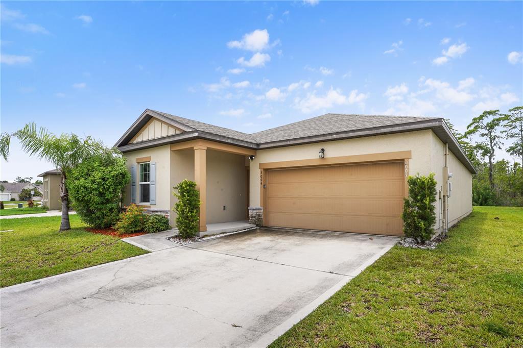 A single-story house with a tan stucco exterior, a two-car garage, and a concrete driveway — 3004 NEVERLAND DRIVE, NEW SMYRNA BEACH, FL