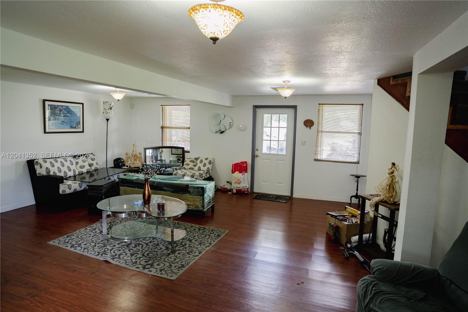 A living room features wood-look flooring, white walls, a glass coffee table, and a staircase — 10337 NE 120TH, Okeechobee FL 34972, OKEECHOBEE, FL