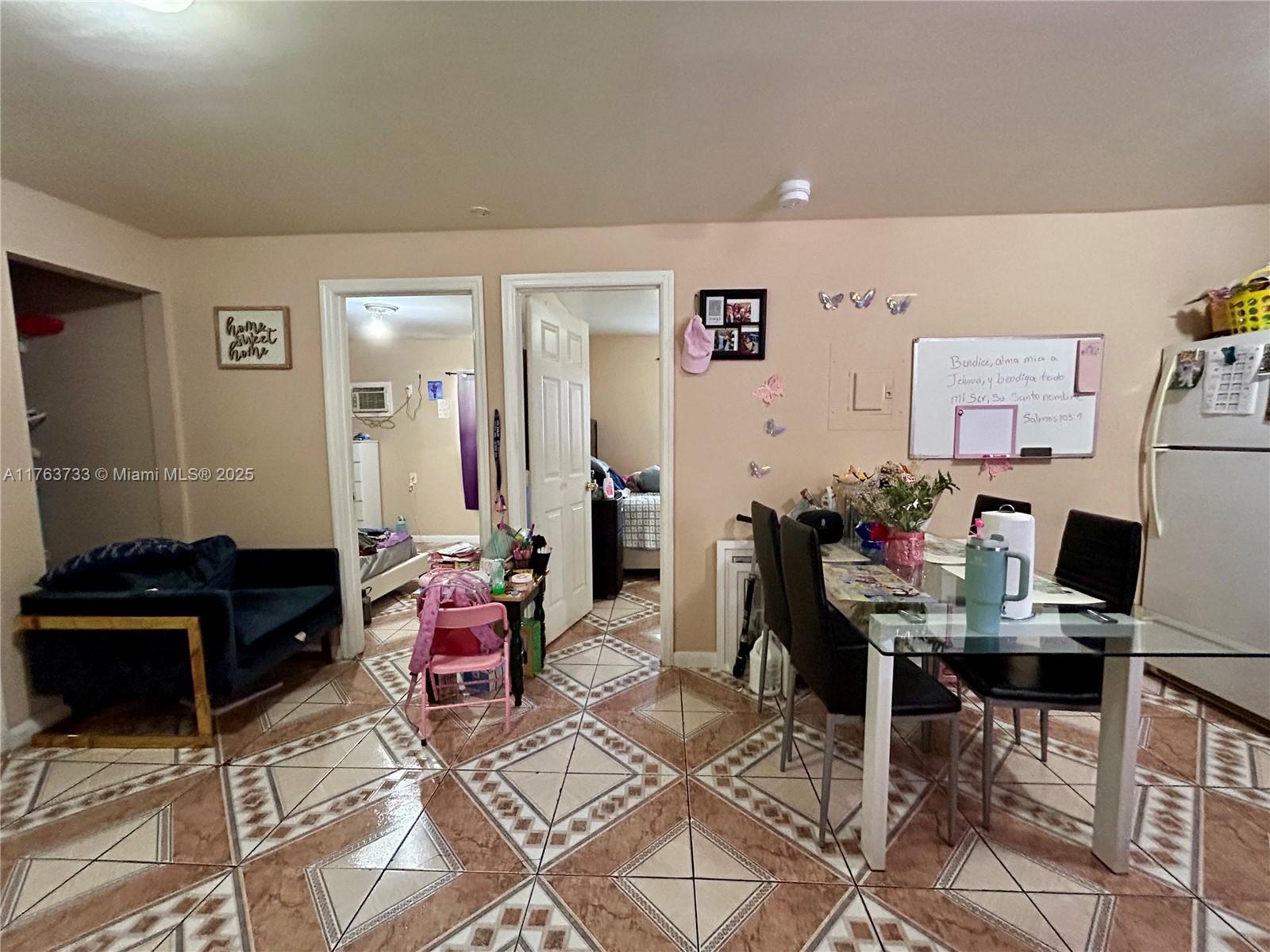 A dining area with a glass table and tiled floors leads into two adjacent bedrooms — 1940 Ali Baba Ave, Opa-Locka FL 33054, OPA-LOCKA, FL