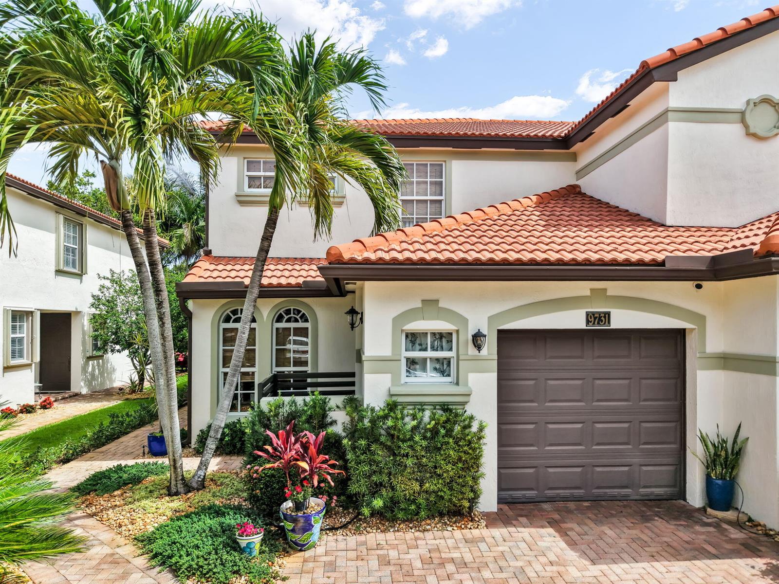 A two-story stucco house features a brown garage door, red tile roof, and palm trees — 9731 Darlington Place, Cooper City FL 33328, COOPER CITY, FL