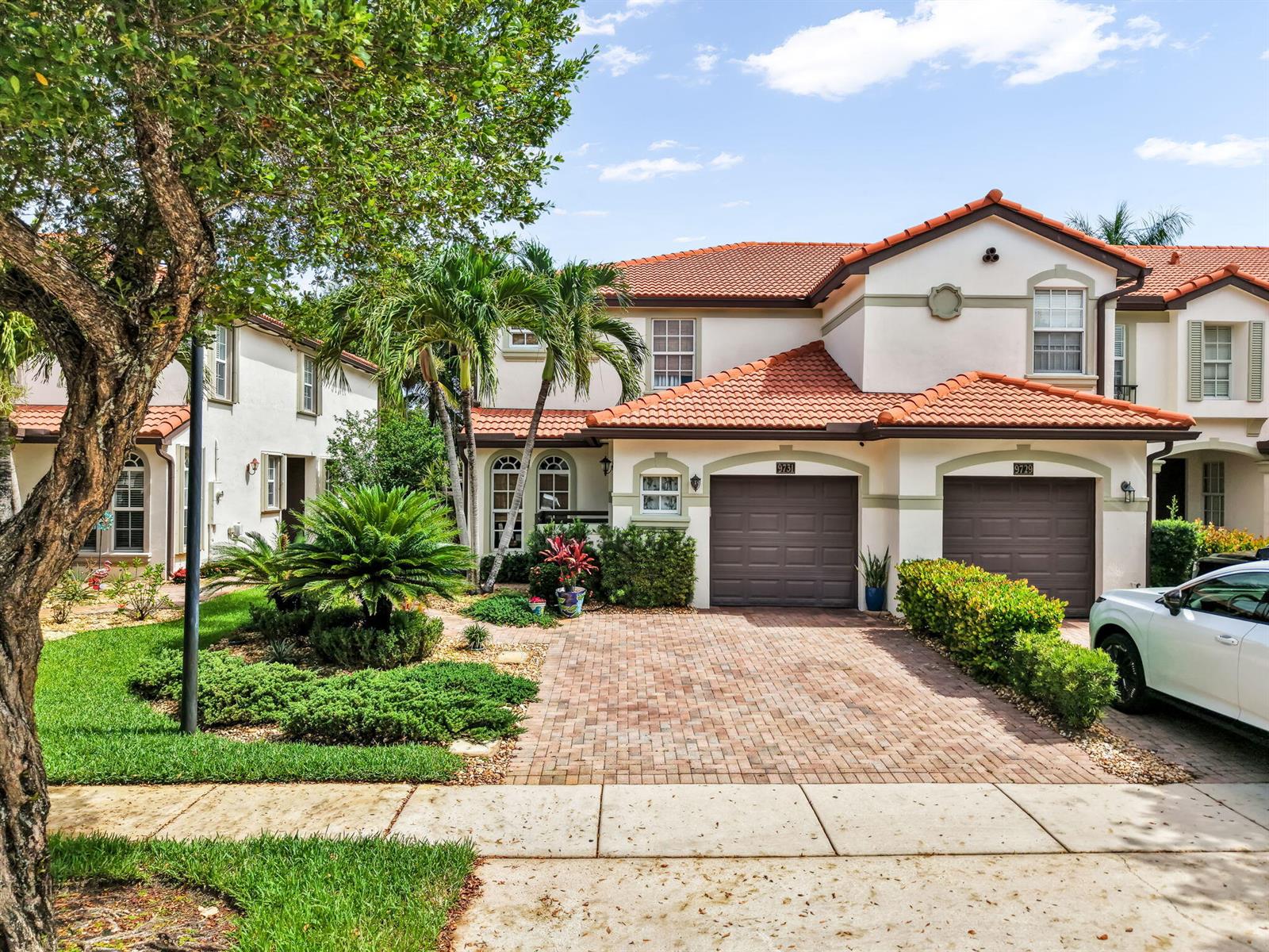 A two-story stucco townhouse with a red tile roof, two garages, and a brick driveway — 9731 Darlington Place, Cooper City FL 33328, COOPER CITY, FL