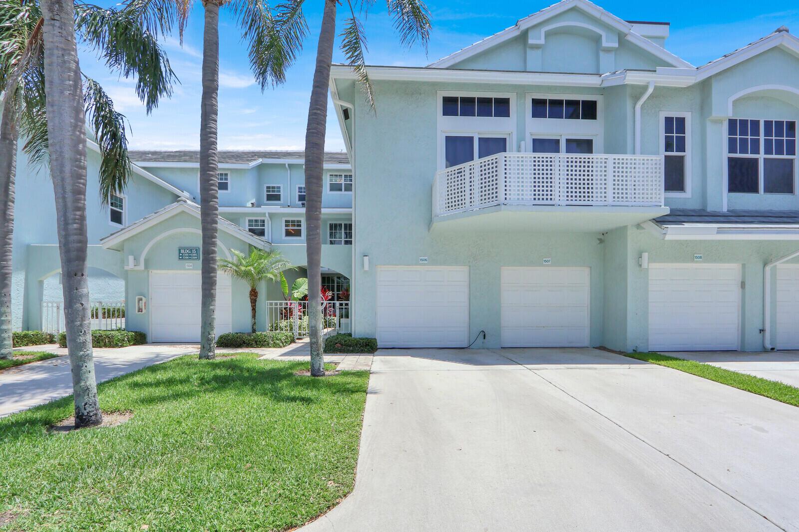 A light green multi-unit residential building features several white garage doors and palm trees — 1506 Mizzenmast Way, Jupiter FL 33477, JUPITER, FL