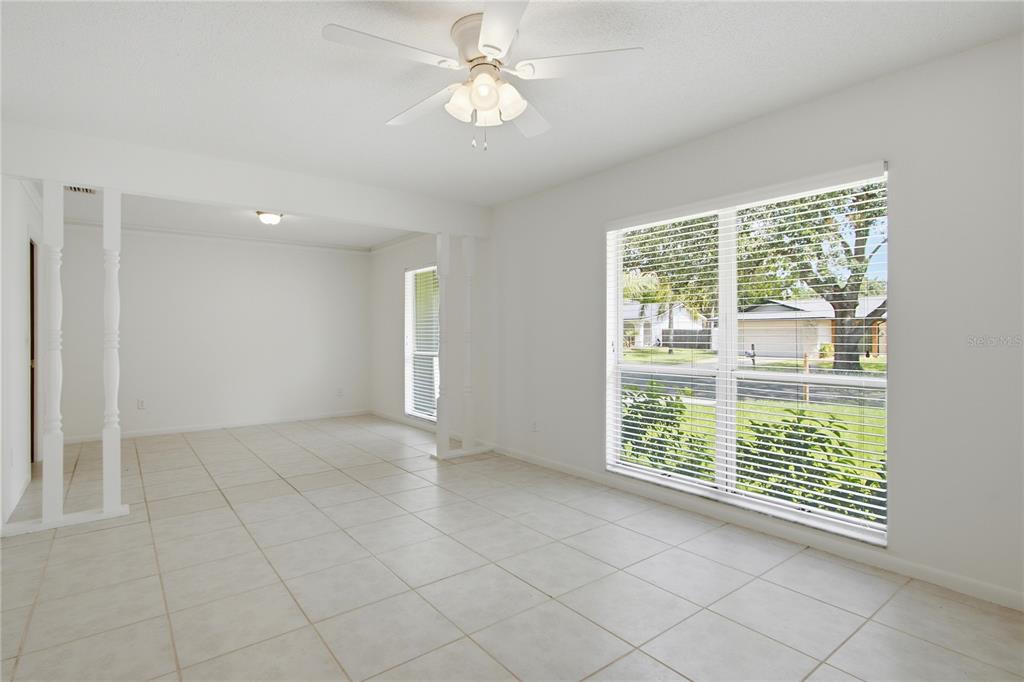 An empty room with white tile floors, a ceiling fan, and large windows — 2028 SUSSEX ROAD, WINTER PARK, FL