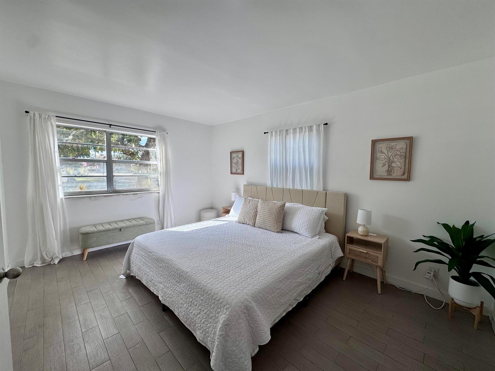 A bedroom features a bed with a beige headboard, white bedding, and wood-look flooring — 202 Lucerne Avenue Unit 9, FL 33460, FL