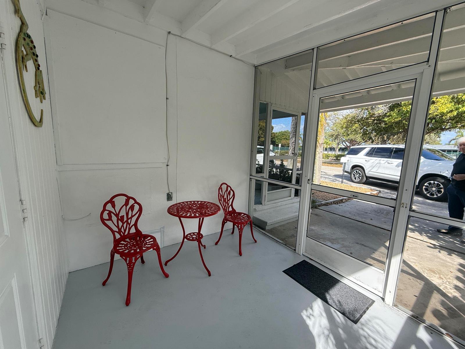 A screened-in porch features a small red bistro set on a light gray floor — 605 E Coast Avenue # 2, Lantana FL 33462, LANTANA, FL