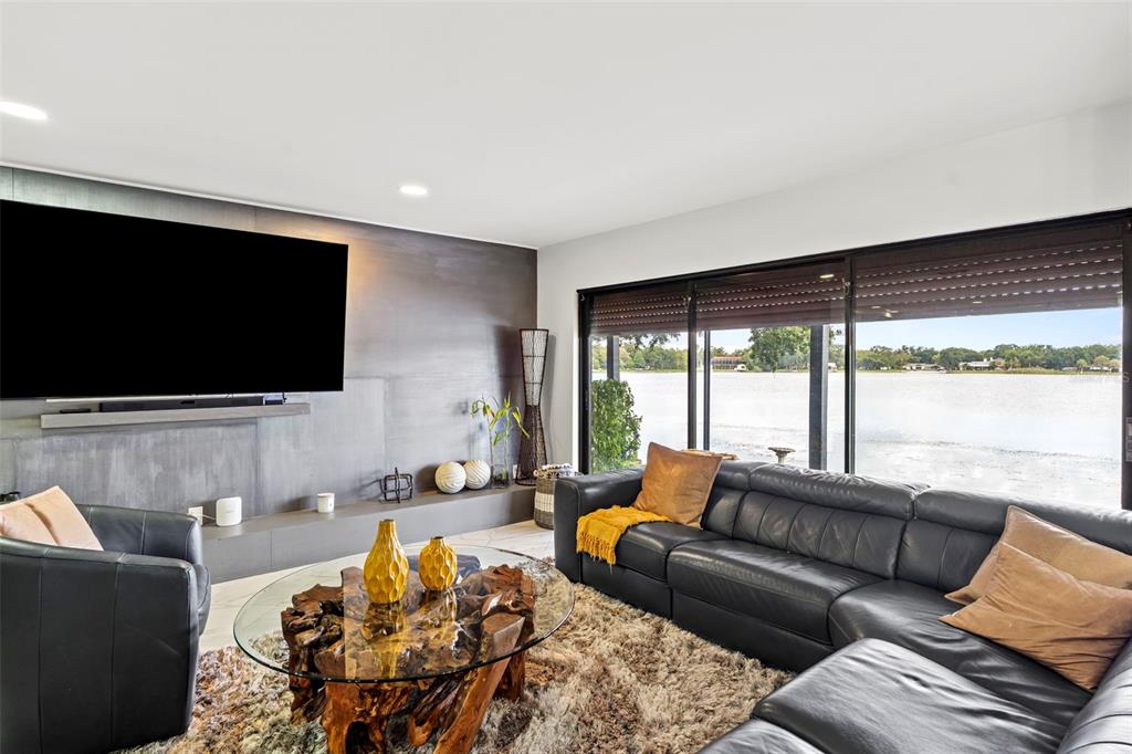 A living room features a dark accent wall, a glass-topped root table, and lake views — 7302 EGYPT LAKE DRIVE, TAMPA, FL