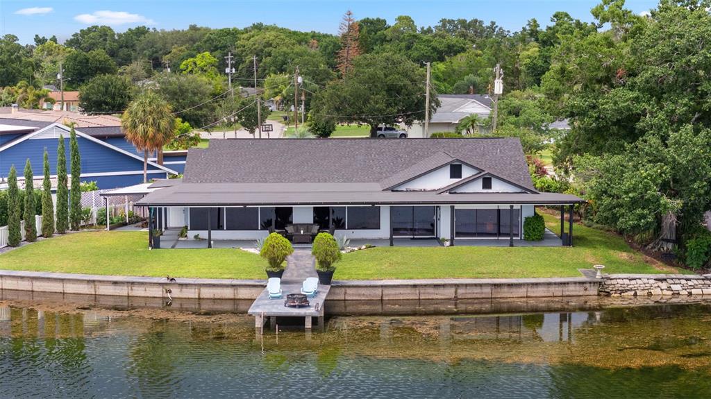 A waterfront house with a dark roof, a covered patio, and a private wooden dock — 7302 EGYPT LAKE DRIVE, TAMPA, FL