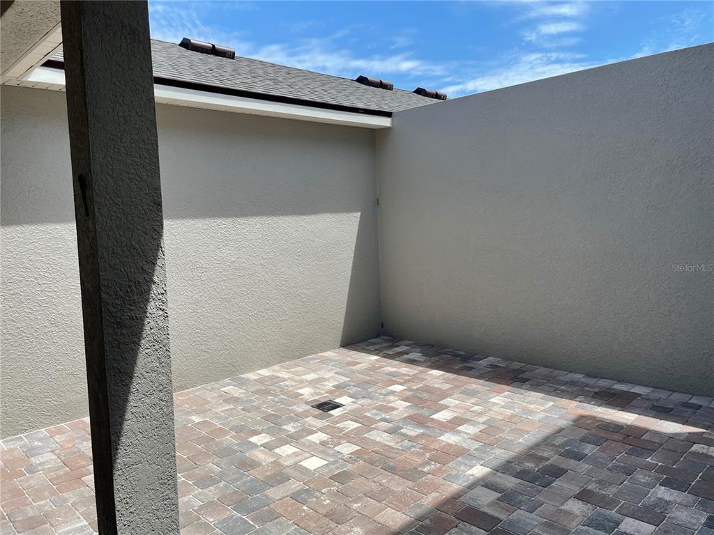 A paved patio is enclosed by high stucco walls under a clear blue sky — 16347 PRAIRIE SCHOOL DRIVE, WINTER GARDEN, FL