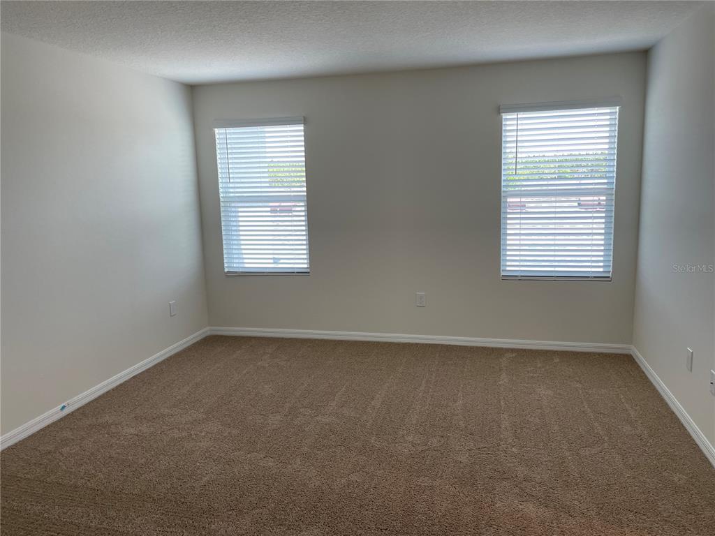 An empty bedroom features beige carpet, light-colored walls, and two windows with white blinds — 16347 PRAIRIE SCHOOL DRIVE, WINTER GARDEN, FL
