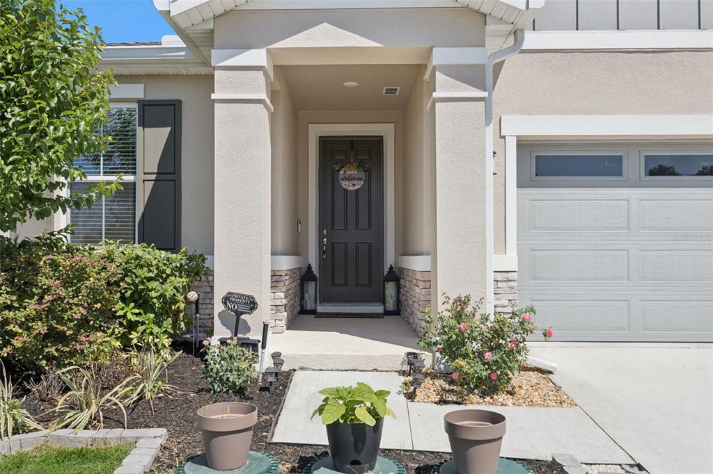 A front entryway with a dark door, stone accents, and a concrete walkway — 10053 SPRING LAKE DRIVE, CLERMONT, FL