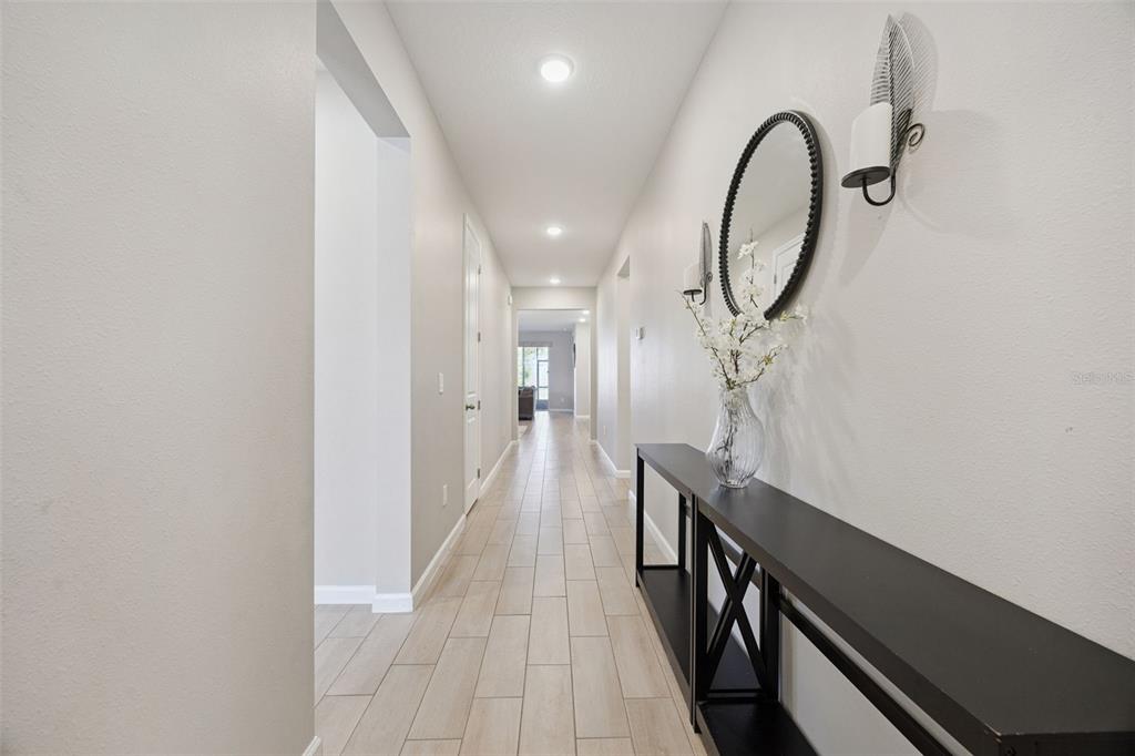 A long hallway with light-colored tile flooring leads to a living area — 10053 SPRING LAKE DRIVE, CLERMONT, FL