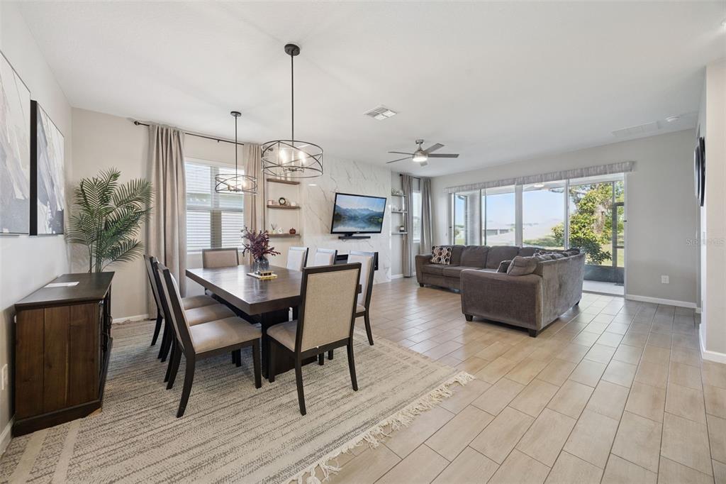 An open-concept dining area and living room featuring tile floors, a marble fireplace, and furniture — 10053 SPRING LAKE DRIVE, CLERMONT, FL