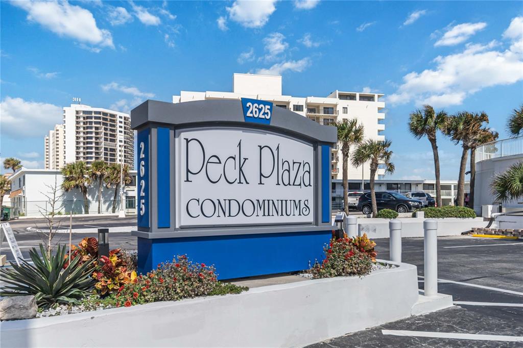 A tall, cylindrical high-rise building with blue accents stands against a bright blue sky — 2625 SOUTH ATLANTIC AVENUE UNIT 12BSW, DAYTONA BEACH SHORES, FL