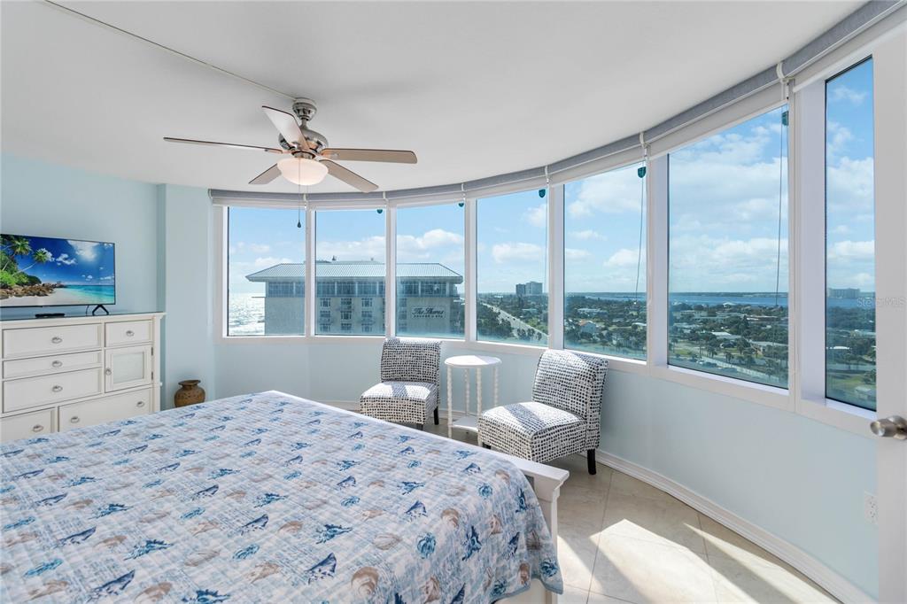 A bedroom features a bed, a dresser, two chairs, and floor-to-ceiling windows with ocean views — 2625 SOUTH ATLANTIC AVENUE UNIT 12BSW, DAYTONA BEACH SHORES, FL