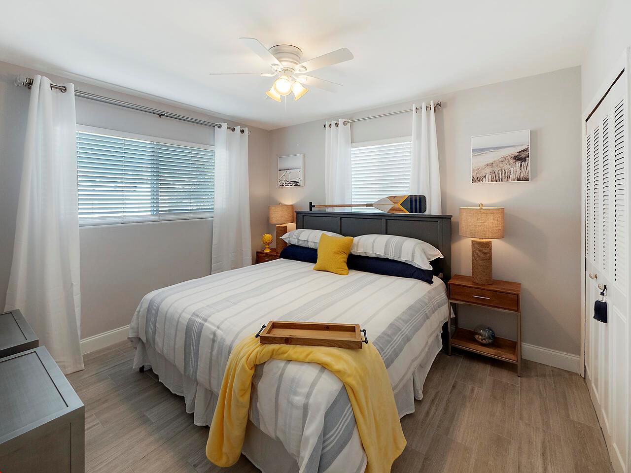 A bedroom features a queen bed with striped bedding, yellow accents, and two bedside lamps — 1236 Beach Road # 1, Riviera Beach FL 33404, RIVIERA BEACH, FL