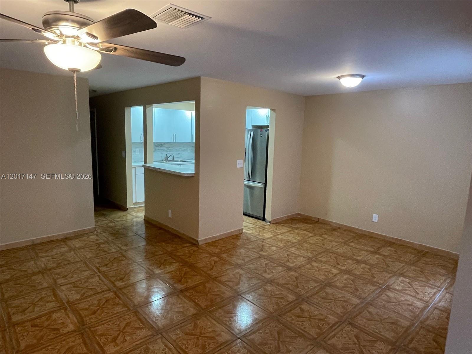 An open-concept living area features tan walls, brown patterned tile flooring, and a kitchen pass-through — 5960 NW 20th St # 5960, Lauderhill FL 33313, LAUDERHILL, FL