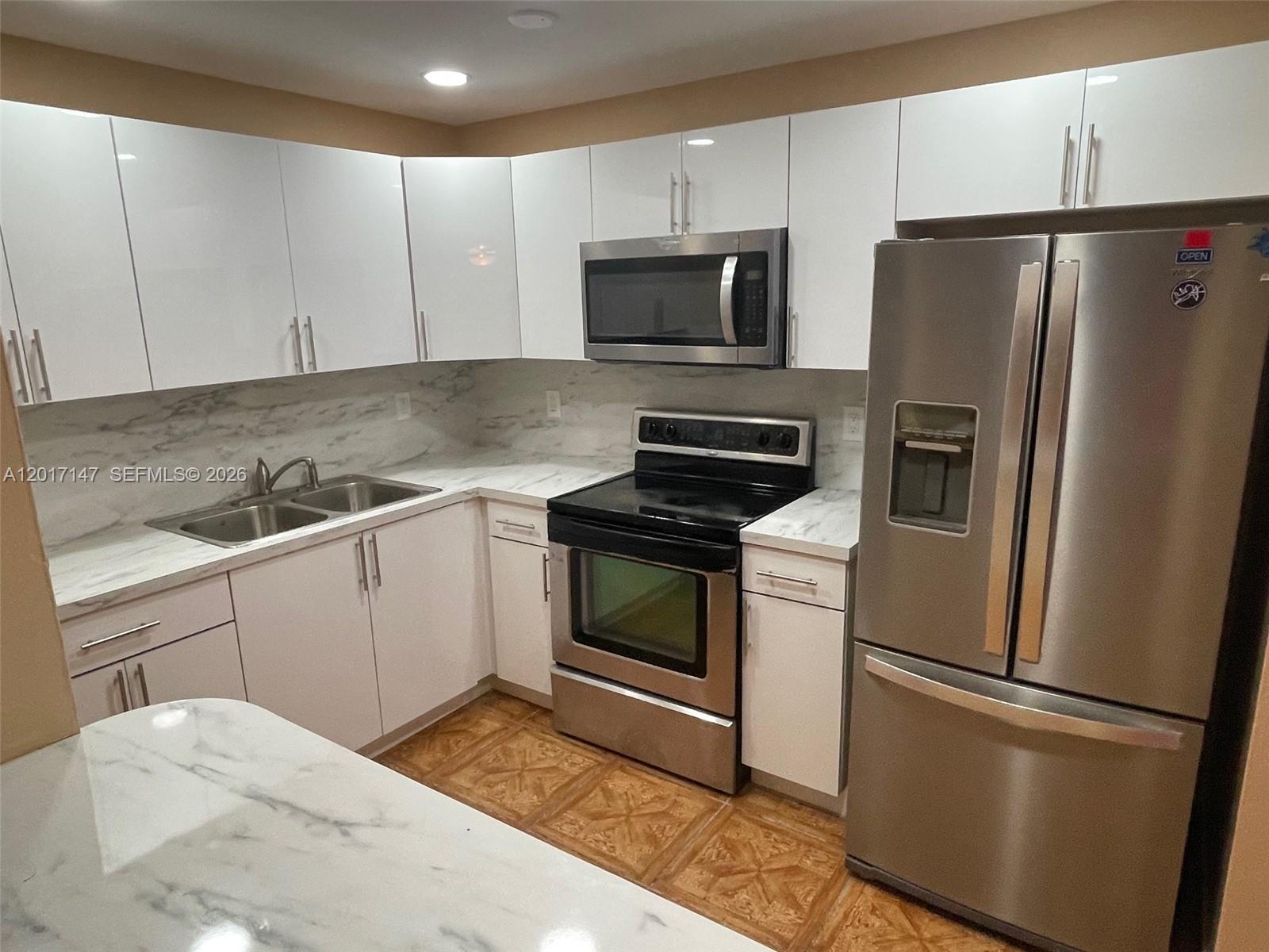 A kitchen features white cabinets, stainless steel appliances, and marble-patterned countertops — 5960 NW 20th St # 5960, Lauderhill FL 33313, LAUDERHILL, FL