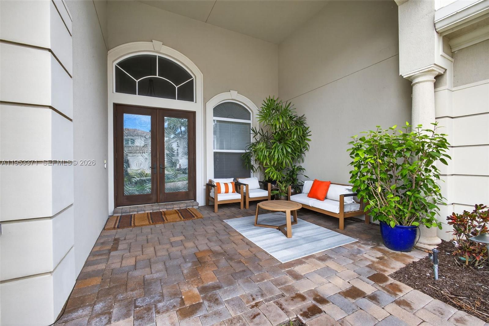 A paved entryway features a double door, two chairs, a bench, and potted plants — 307 Charroux Dr, Palm Beach Gardens FL 33410, PALM BEACH GARDENS, FL