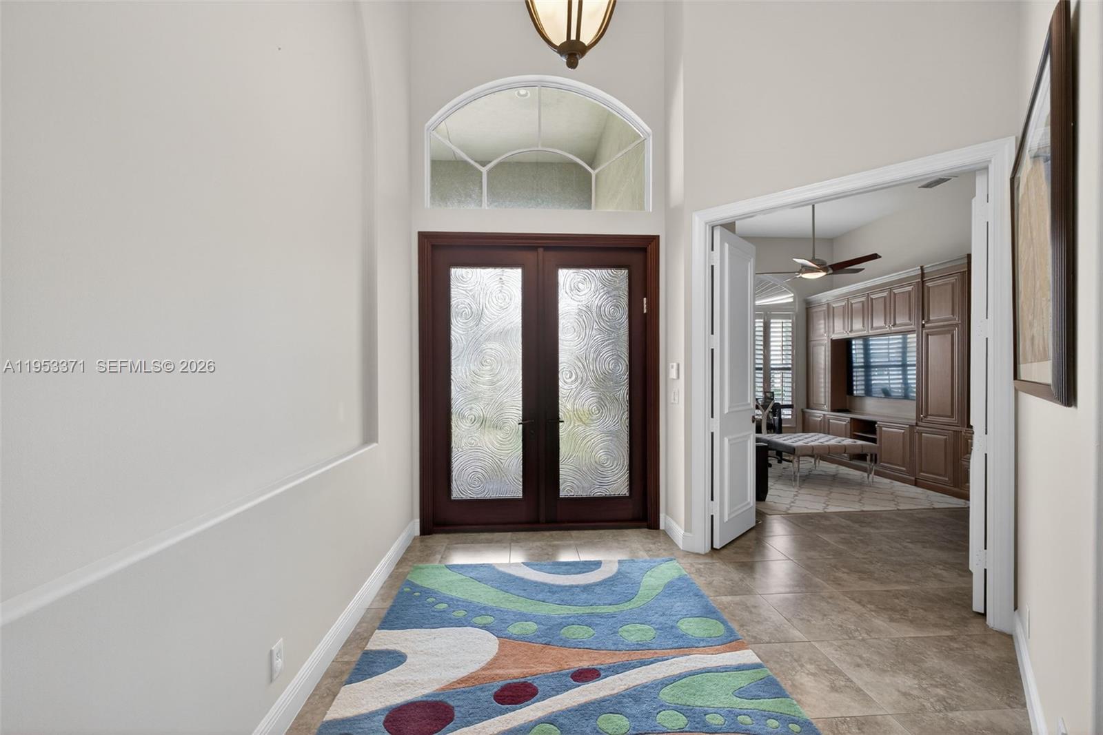 A bright entryway features a patterned rug, double glass doors, and an arched transom window — 307 Charroux Dr, Palm Beach Gardens FL 33410, PALM BEACH GARDENS, FL