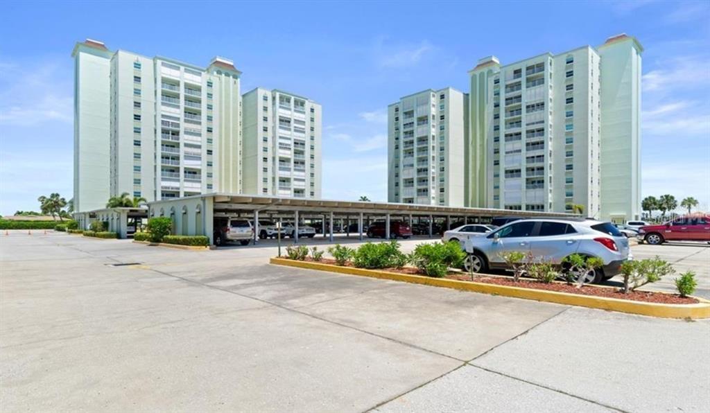A wooden dock extends into the water next to a tall residential building — 400 64TH AVENUE UNIT 405, ST PETE BEACH, FL