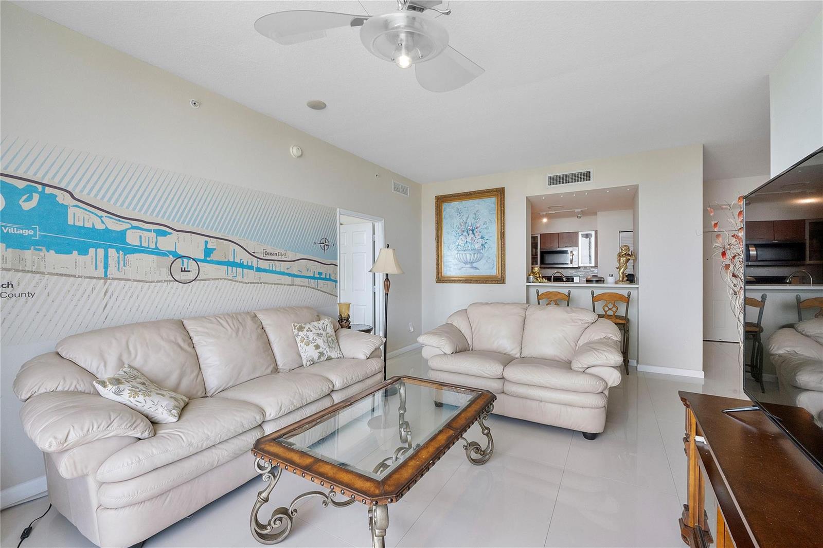A living room features two beige leather sofas, a glass coffee table, and a wall mural — 625 Casa Loma Boulevard # 1608, Boynton Beach FL 33435, BOYNTON BEACH, FL