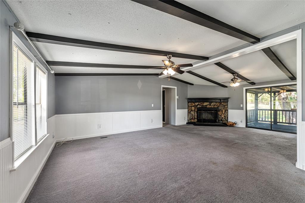 A kitchen features white cabinets, stainless steel appliances, granite-look countertops, and wood-look flooring — 5600 SE 39TH STREET, TRENTON, FL