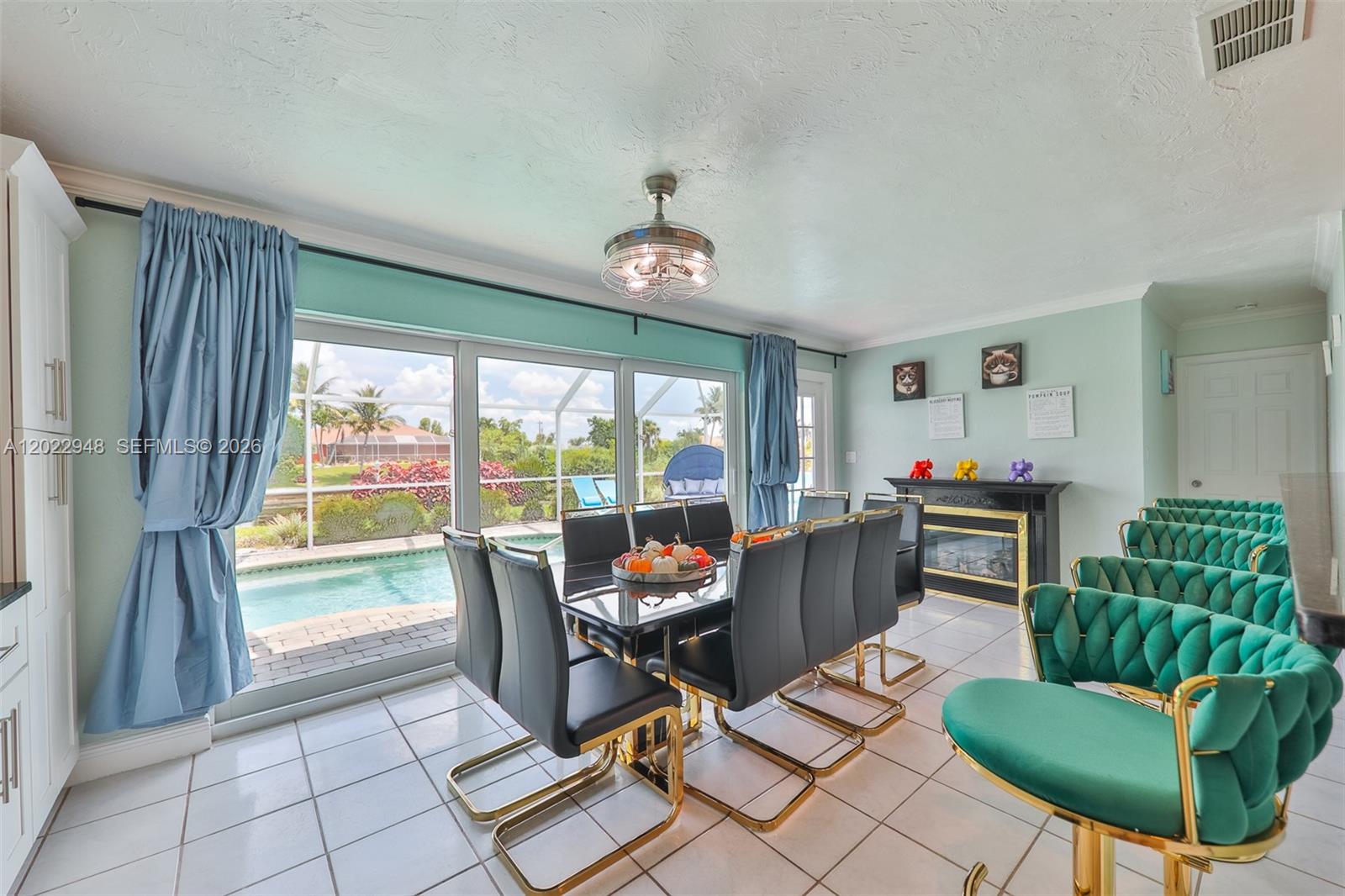 A dining room features a glass table, black chairs, green velvet stools, and pool views — 503 SW 17 St, Cape Coral FL 33990, CAPE CORAL, FL
