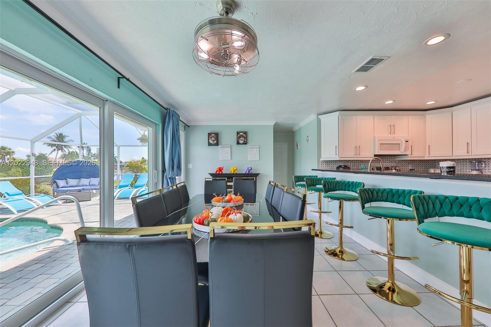 A dining area with a glass table and green bar stools overlooks a pool patio — 503 SW 17 St, Cape Coral FL 33990, CAPE CORAL, FL