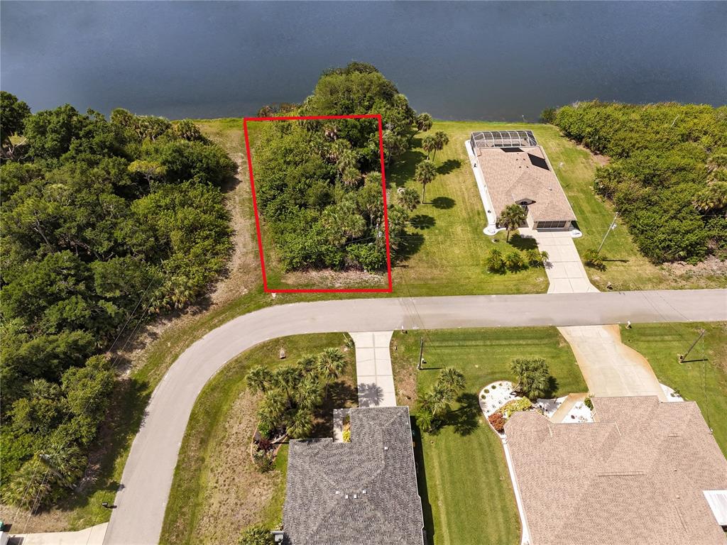 An aerial view shows a vacant, wooded waterfront lot outlined in red between two houses — 123 GARLAND WAY, ROTONDA WEST, FL