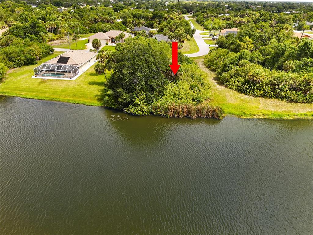 An aerial view shows a wooded waterfront lot marked by a red arrow — 123 GARLAND WAY, ROTONDA WEST, FL