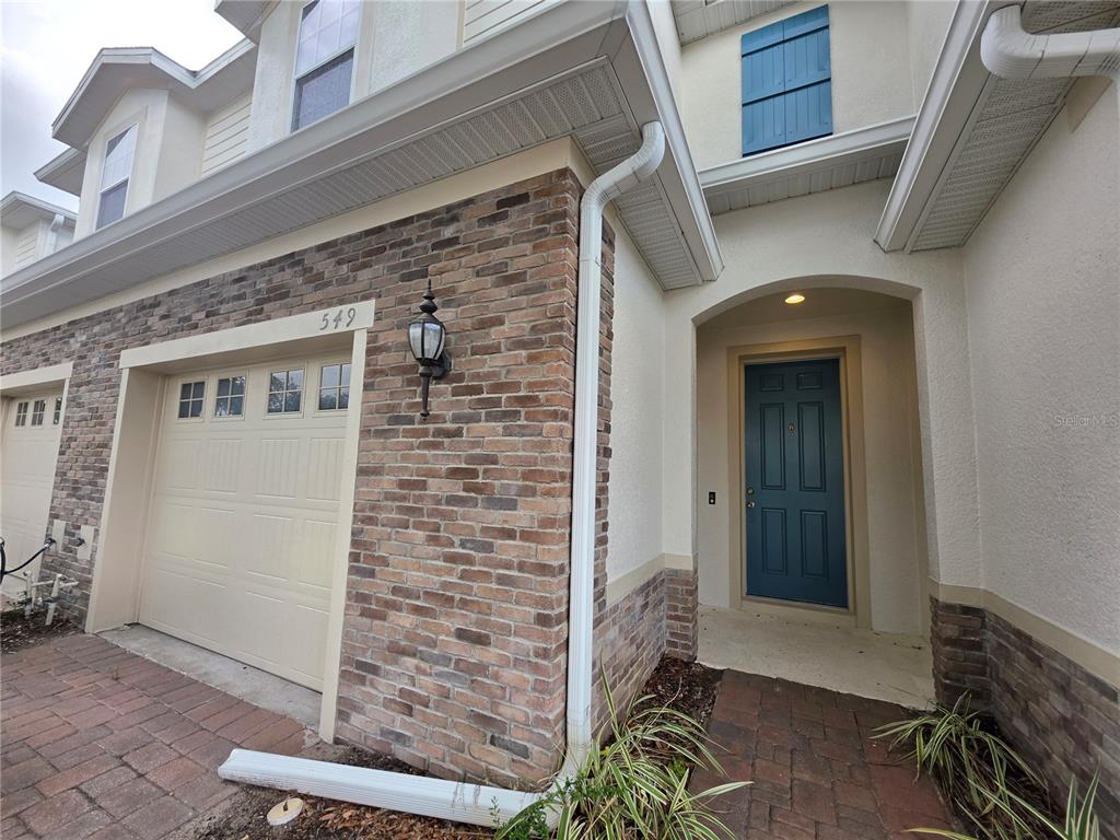 The exterior of a two-story home features a brick facade, a garage, and a blue door — 549 BETHESDA COURT, OVIEDO, FL