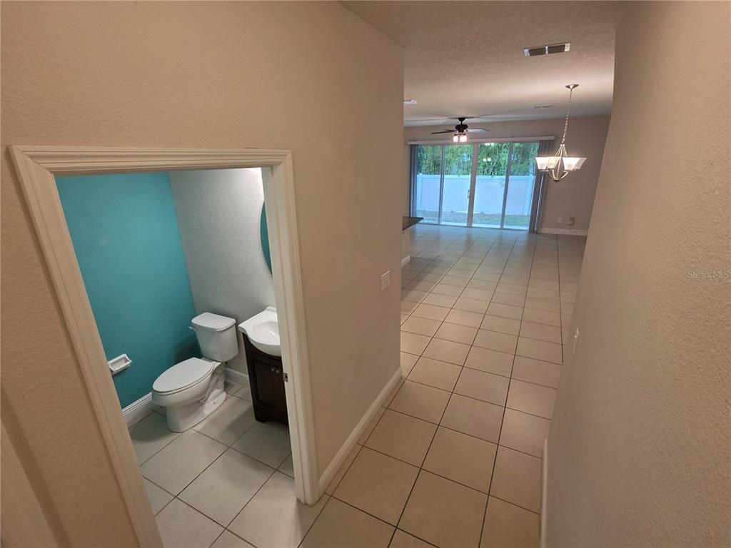 A tiled hallway leads to a powder room with a teal wall and a living area — 549 BETHESDA COURT, OVIEDO, FL