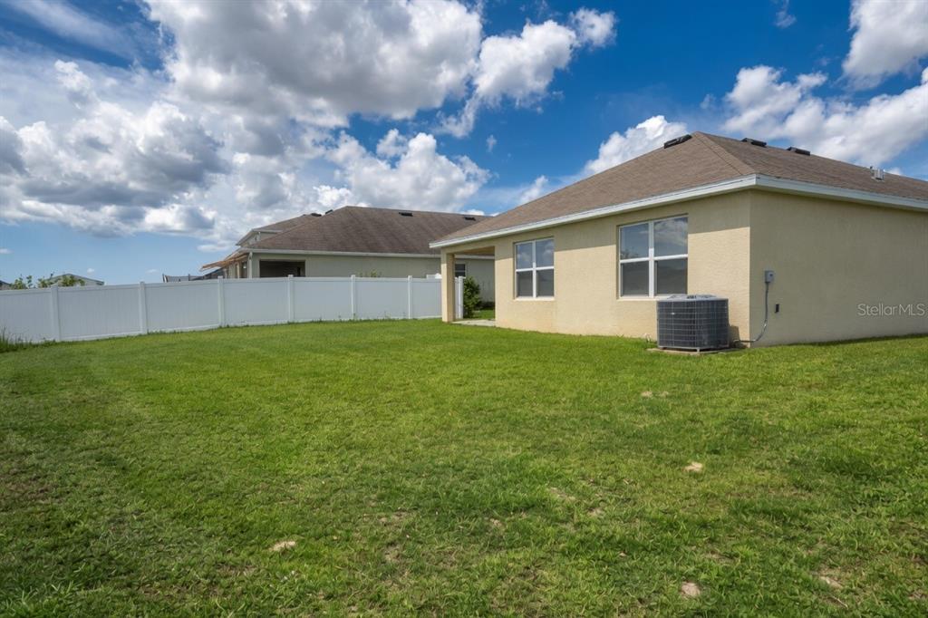 A view of a grassy backyard with a white vinyl fence and a house exterior — 3499 N VONNEGUT PT, BEVERLY HILLS, FL