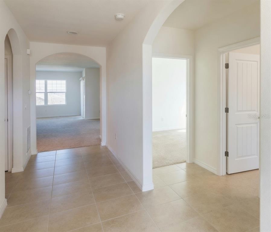 A tiled hallway leads to an arched entryway opening into a carpeted living area — 3499 N VONNEGUT PT, BEVERLY HILLS, FL