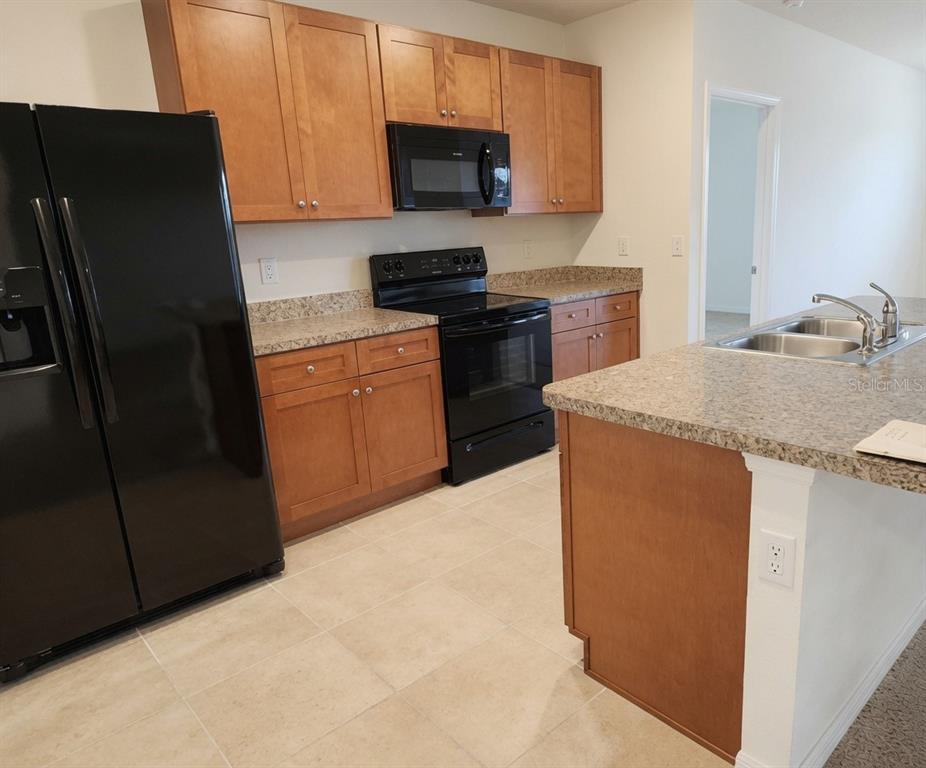 A kitchen features wood cabinets, black appliances, granite countertops, and a central island — 3499 N VONNEGUT PT, BEVERLY HILLS, FL
