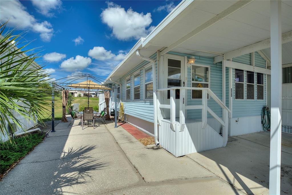 A light blue mobile home features a concrete patio with a metal gazebo and umbrella — 305 ARNOLD PALMER DRIVE, DAVENPORT, FL