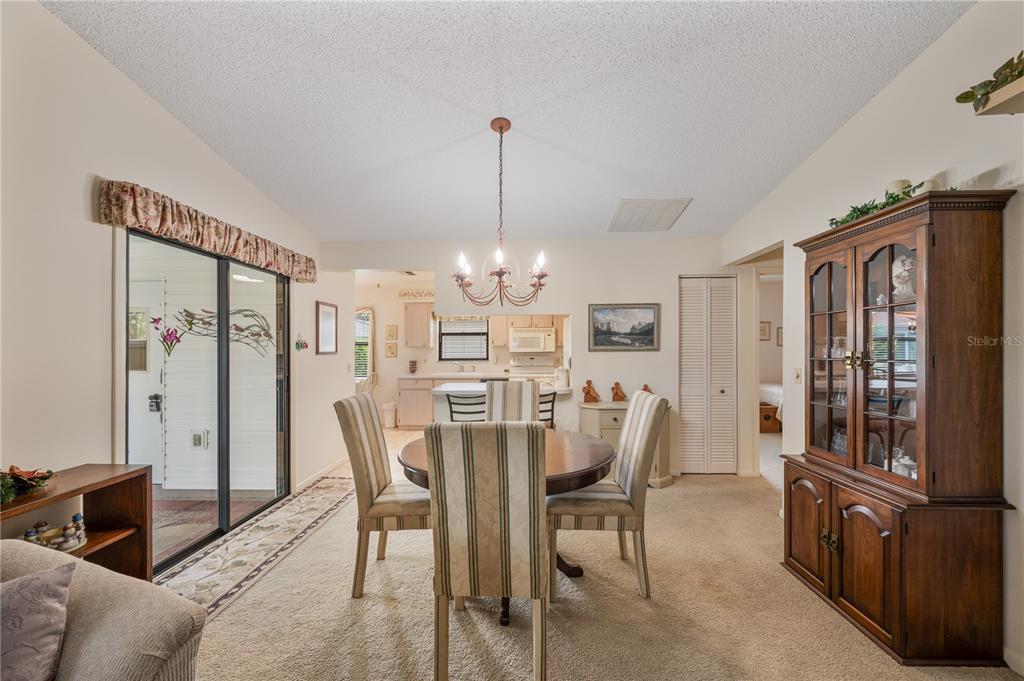 A dining area with a round wooden table and chairs opens into a living room — 4918 PLEASANT HOLLOW TRAIL, LAKELAND, FL