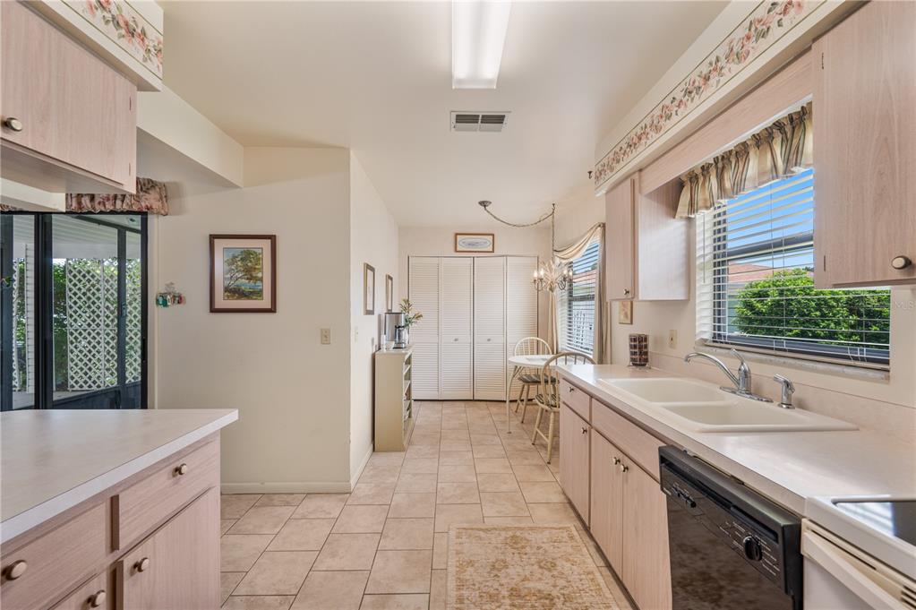A kitchen with light wood cabinets, tile flooring, a double sink, and a dining area — 4918 PLEASANT HOLLOW TRAIL, LAKELAND, FL