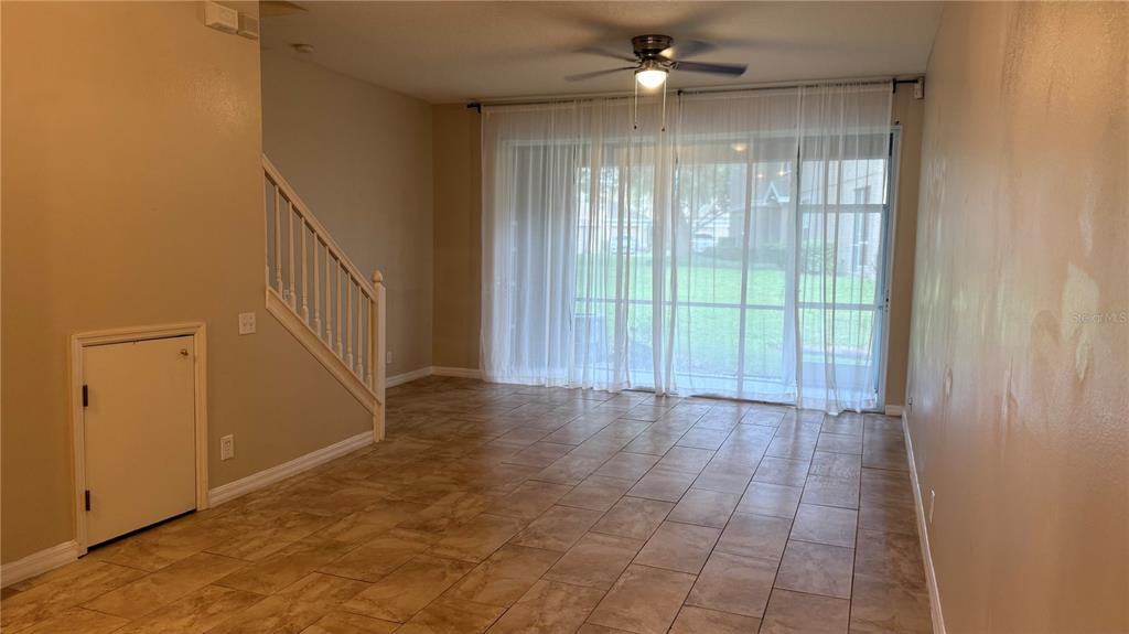 A living room features tile flooring, a staircase with a storage closet, and sliding glass doors — 4135 BISMARCK PALM DRIVE, TAMPA, FL