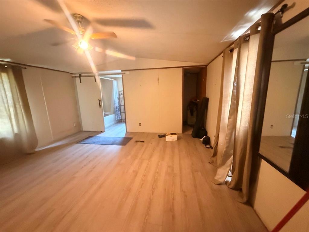 A bedroom with light wood-look flooring, a ceiling fan, and an attached bathroom — 10105 MCMAHON AVENUE, HASTINGS, FL